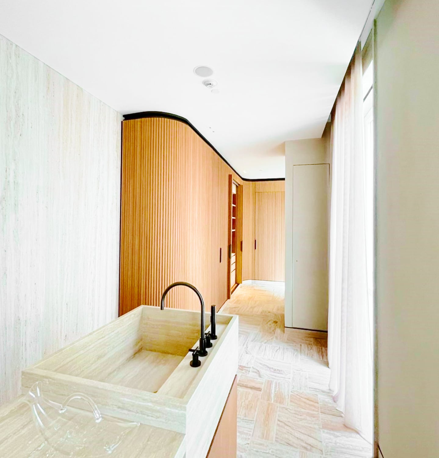 Camera d'hotel con lavabo in pietra e parete curva in legno