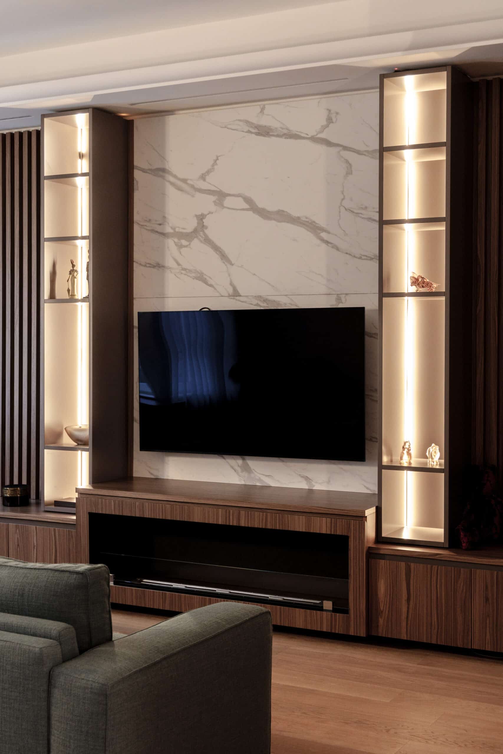Living room with a marble wall, a custom TV unit and lit display shelves